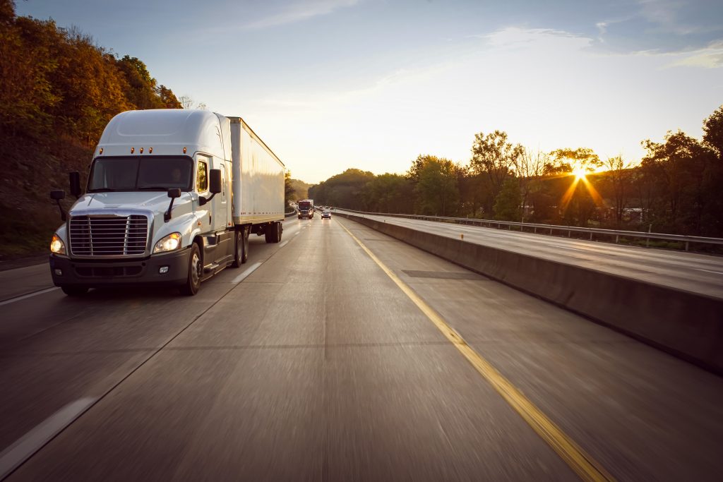 White 18 wheeler truck on highway at sunrise